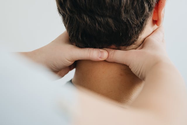 Person, die eine Nackenmassage erhält, bei der beide Hände Druck auf den Nacken ausüben.